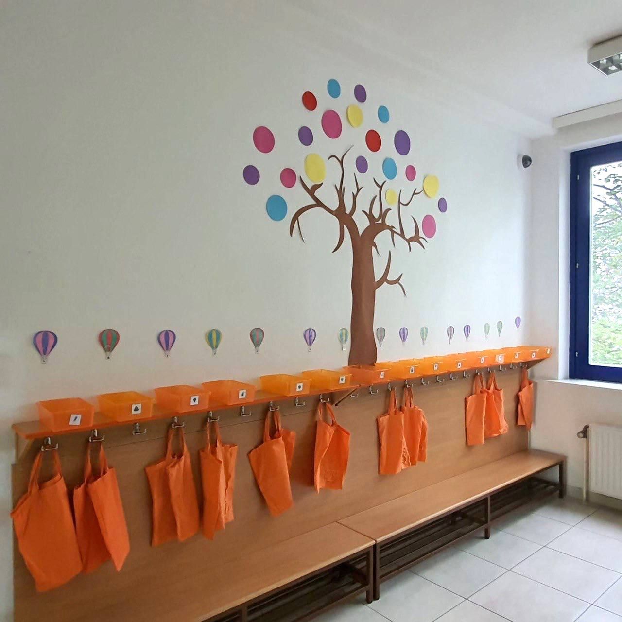 Garderobe mit bemaltem Baum und orangen Taschen