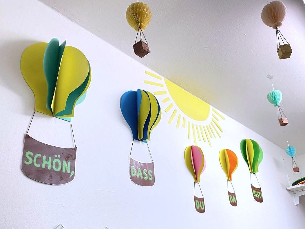 Papierballons an der Wand: "Schön, dass du da bist"