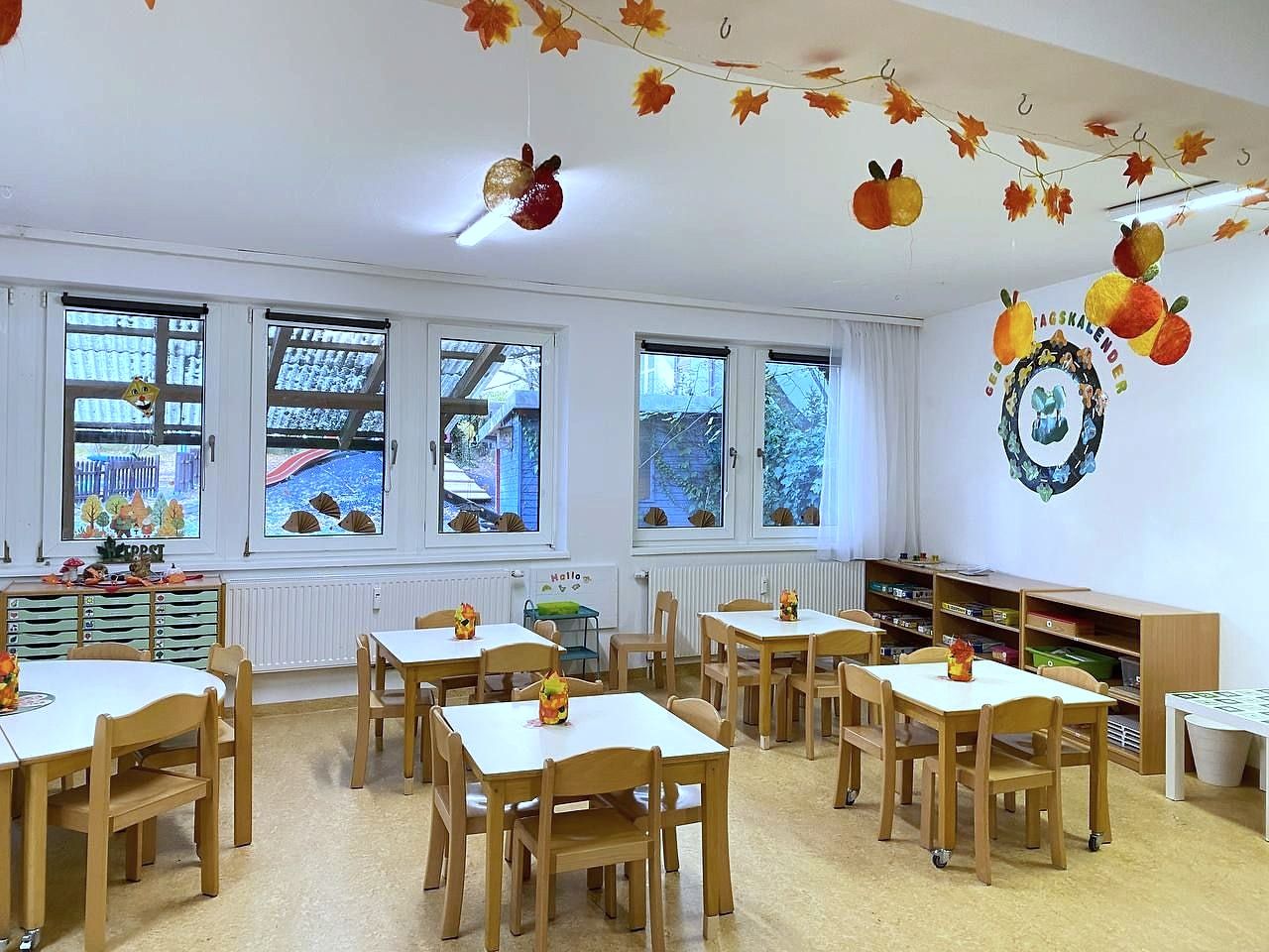 Heller Gruppenraum mit Tischen und Herbstdekoration