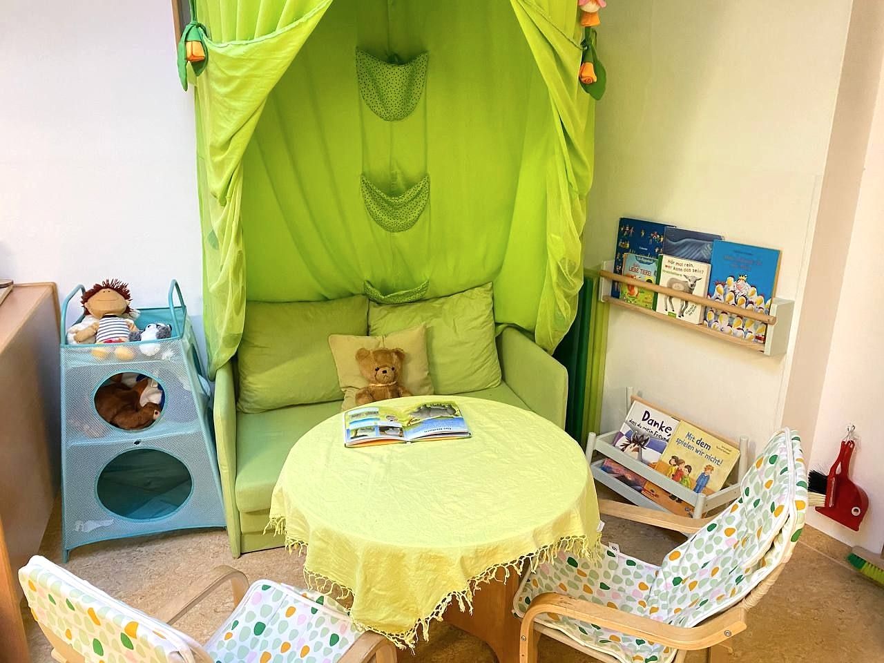 Grüne Kuschelecke mit Sofa, Büchern und rundem Tisch