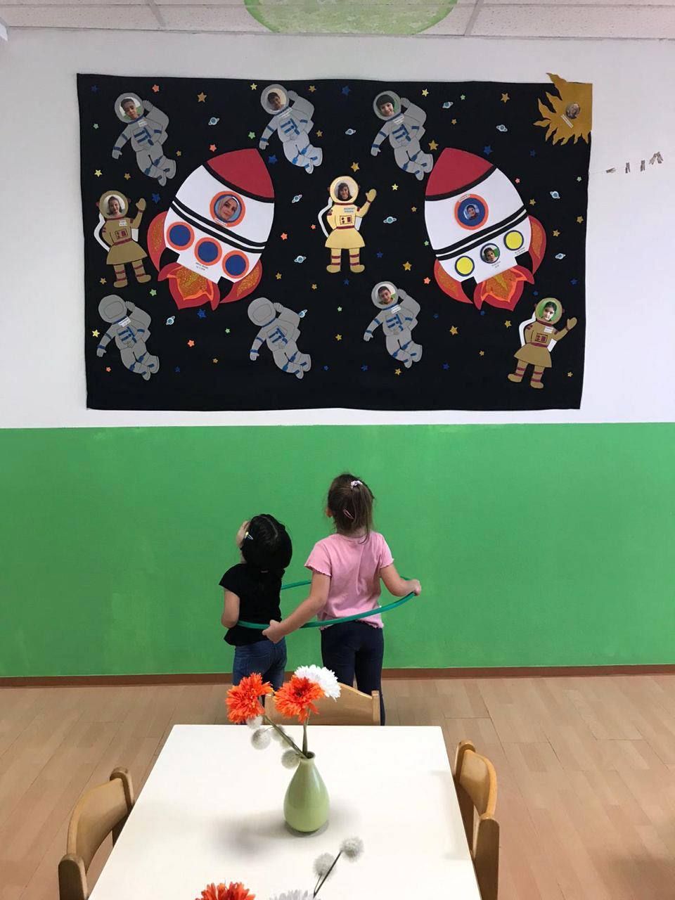 Kinder spielen mit einem Reifen vor einer Weltraum-Wanddekoration