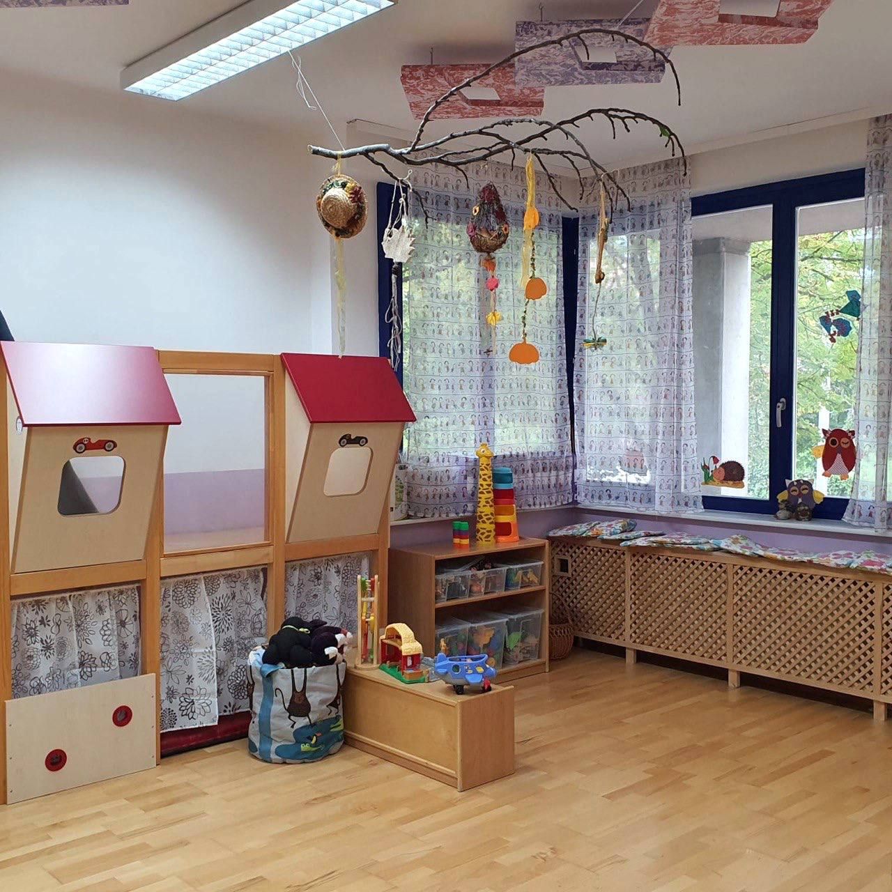 Spielraum mit Holz-Spielhäusern und Kuscheltieren