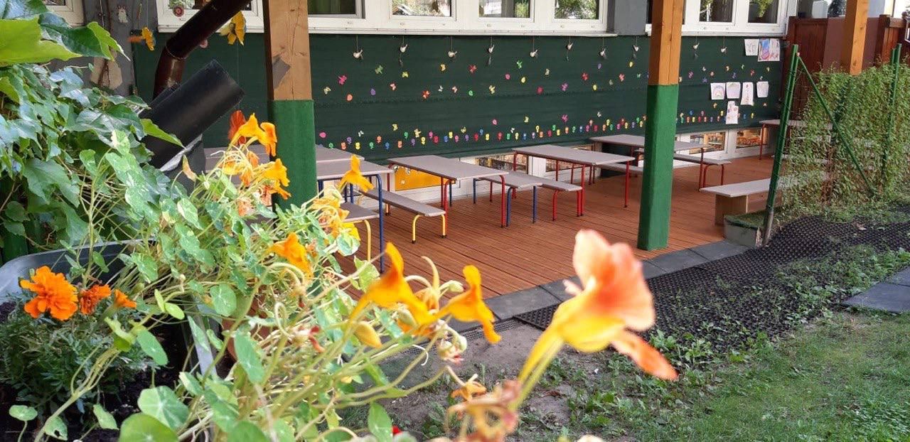 Überdachte Terrasse mit Sitzbänken im Garten des Kindergartens